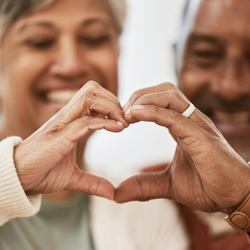 A happy senior couple with making a heart shape with their hands